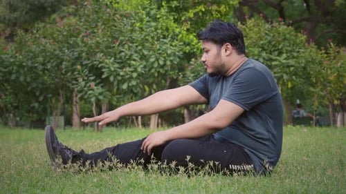 overweight man trying toe touching exercise while sitting at park