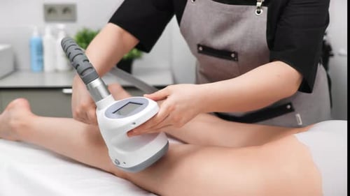 Massage Therapist Using Machine on Woman's Thigh