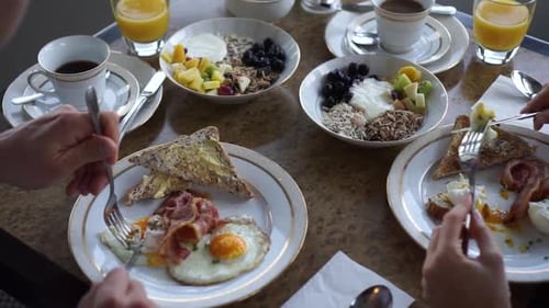SLOWMO - Man and woman having bacon and egg, homemade muesli, coffee and orange juice for breakfast