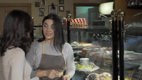 Charming Young Woman Engaging with a Customer at Her Delightful Bakery