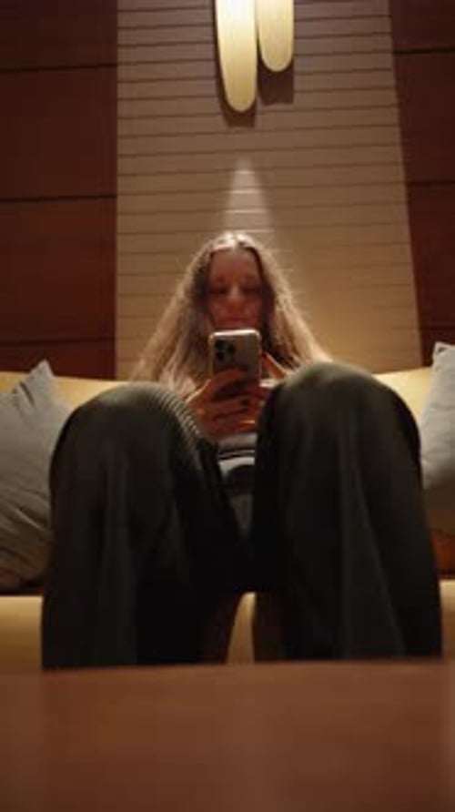 Woman Using Mobile Phone While Sitting on Couch