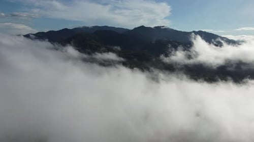 Aerial shot revealing mystic allure of hill covered by low-lying clouds