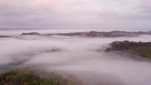 Aerial view of foggy countryside with villa and cypress trees, Italy.
