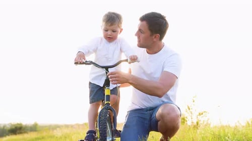 Father Helps Young Son Learn to Ride Bike