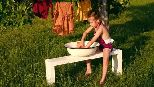 Child Washing Clothing in Rural Sunlight Setting
