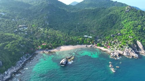 A tropical island with resorts surrounded by clear waters. Drone view.