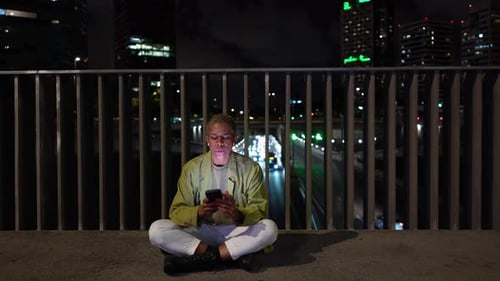 Young Person Using Smartphone on Urban Overpass at Night