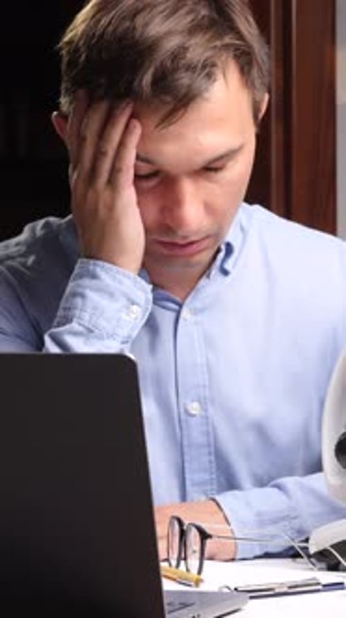 Stressed Man Working at Desk With Laptop
