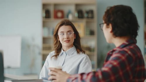 Young woman and man chatting during coffee break in a modern office