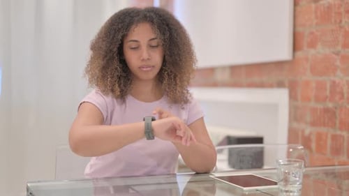 Woman Uses Smart Watch at Table Indoors