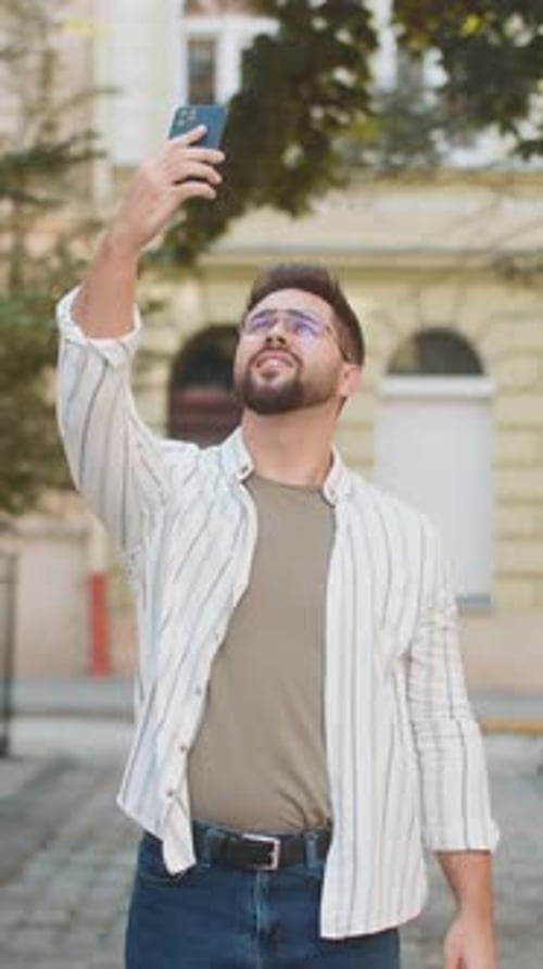 Frustrated Young Man Trying to Catch Signal on Smartphone for Better Connection in City Street