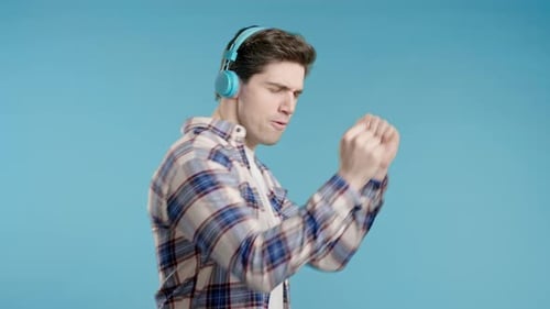 Young Positive Man Listening Music Enjoying with Headphones Blue Studio