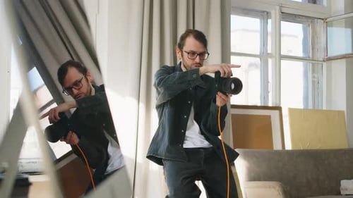 Young Male Photographer with Professional Camera Working in Studio