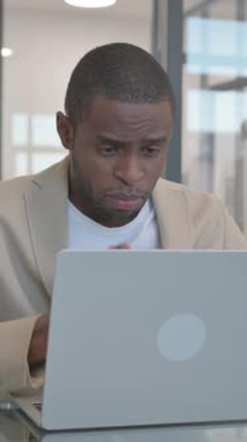 Surprised Man Reacting to News on Laptop Indoors