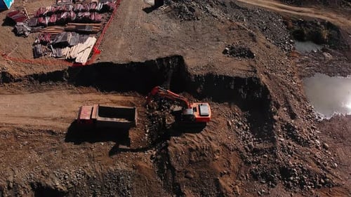 Excavator Loading Dump Truck on Construction Site Aerial View