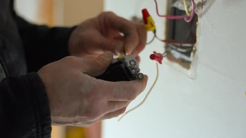 Electrician Installing Electrical Outlet and Connecting Wires Inside a Wall Box During Home