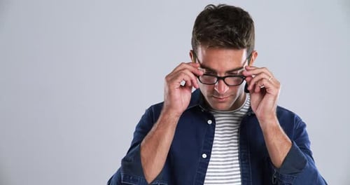 Gesicht, Lächeln und Brille mit einem jungen Mann im Studio isoliert auf grauem Hintergrund zum Entspannen