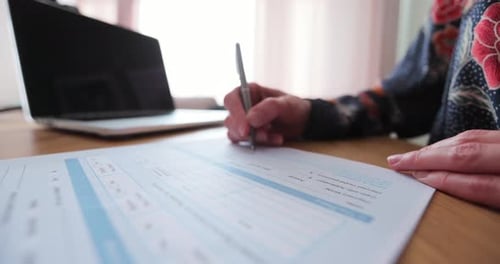 Woman Filling and Signing Tax Form at Desk