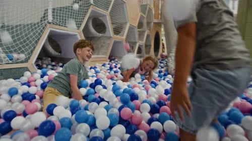 Enfants de la génération Alpha jouant avec des balles dans une fosse
