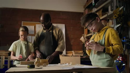 Children and Teacher Crafting Wooden Toys in Carpentry Workshop