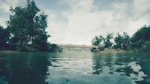 Calm River View with a Bridge Surrounded By Trees on a Cloudy Day