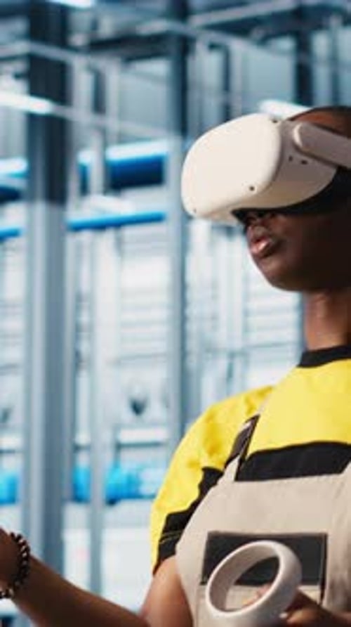 Vertical Video Engineer Wearing VR Headset in Smart Factory Looking at Data to Do Optimizations