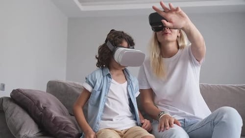 Child and Adult Experience Virtual Reality Headsets on Couch