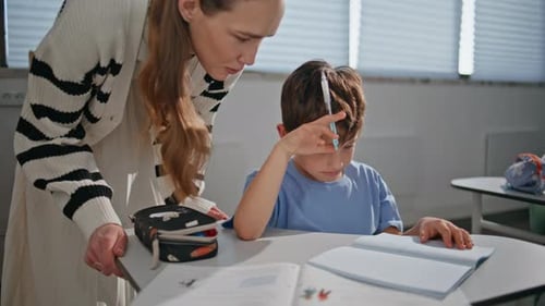 Teacher Helping Young Student With Class Assignment