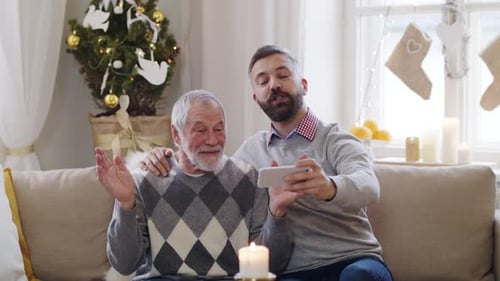 Senior Man and Adult Son Video Chatting at Christmas
