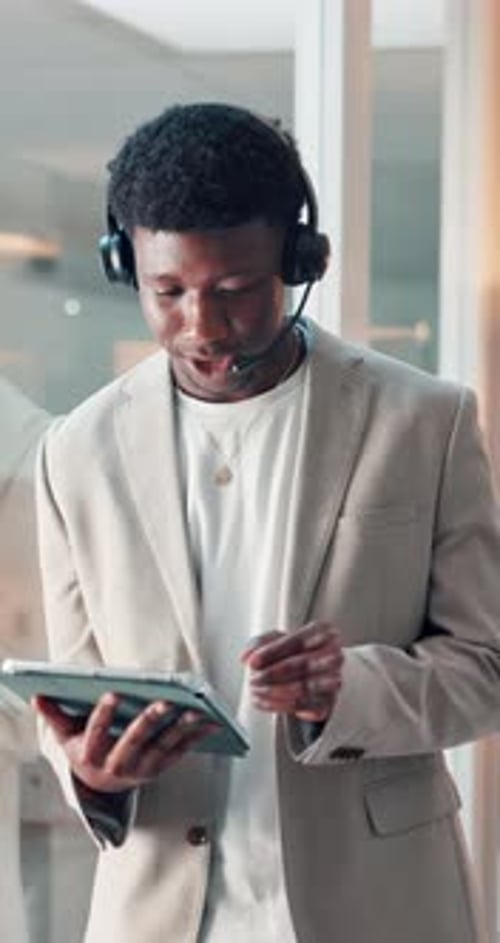 Man Wearing Headset Using Tablet in Modern Office