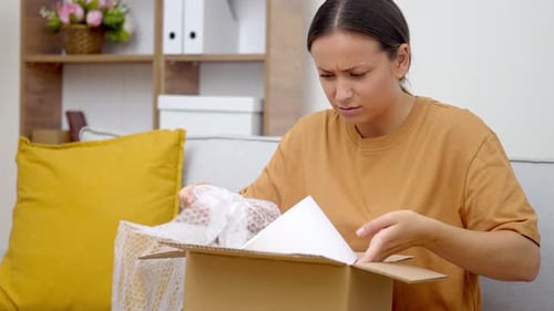 Young Woman Opening Confusing Package at Home