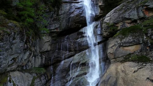 4k Drone Slowly Ascends Cascading Waterfall Nestled In between Mountain Landscape With Pine Trees In