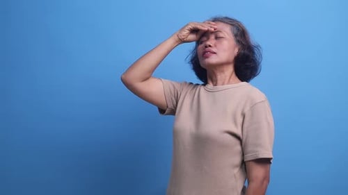 Woman Experiencing Pain Standing Against Blue Background