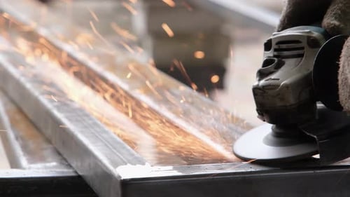 Worker Smoothing Welded Metal with Power Tool