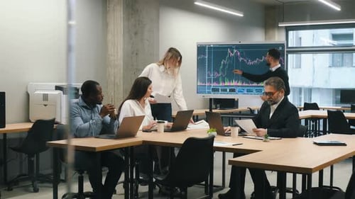 Daten auf dem Bildschirm. Eine Gruppe von Büroangestellten ist zusammen drinnen.