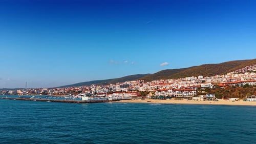 Coastal view of a beach town by the sea under clear blue skies.