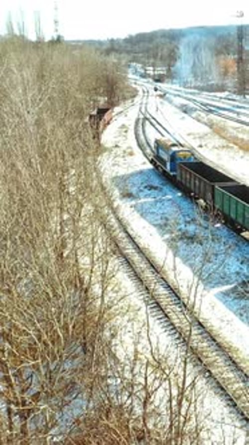 A freight train with containers moves along the rails in the direction of the city in a winter day.