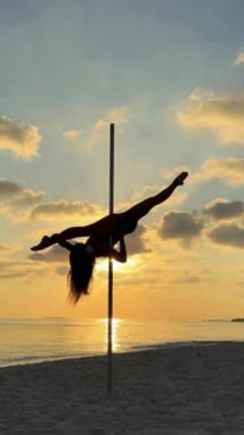 Pole Dancer exécutant Split Trick sur la plage au coucher du soleil