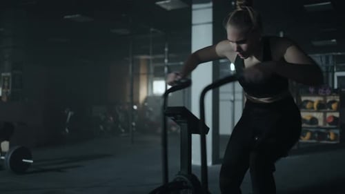 Sportswoman is Training on Stationary Bike in Gym Beautiful Woman Exercising Rotating Pedals