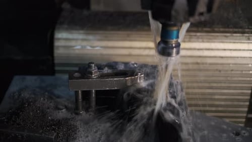 Iron milling in a cnc machine tools with water cooling. Machining of metal parts in the factory.