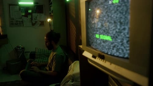 Man Working on his Laptop in Dimly Lit Retro Room with Neon Green Lighting