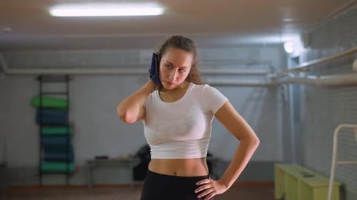 Femme en haut blanc et leggings noirs essuyant le pull avec une serviette bleue
