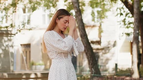 Young Woman Praying Peacefully in a Sunny Park