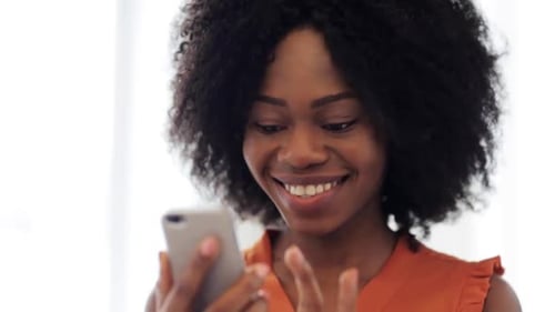 Smiling woman using smartphone indoors, close-up