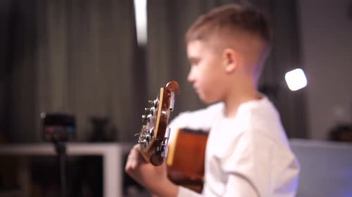 Young Boy Plays Acoustic Guitar Indoors