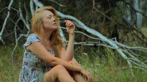 Woman Holding Flower While Sitting in Nature
