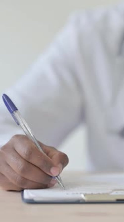 Gros plan d'un médecin africain travaillant sur des documents médicaux, Vidéo verticale