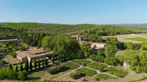 Aerial orbiting shot of a abbey surrounded by field in the French countryside