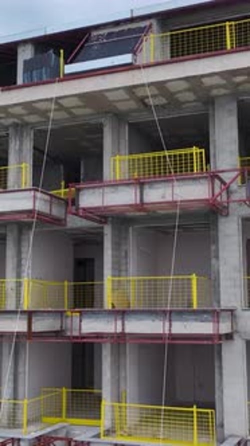 Vertical Video of a Towering Building Frame Standing Against a Blue Sky With Construction Materials