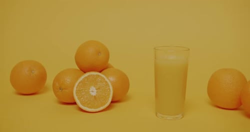 Oranges and a Glass of Juice on Yellow